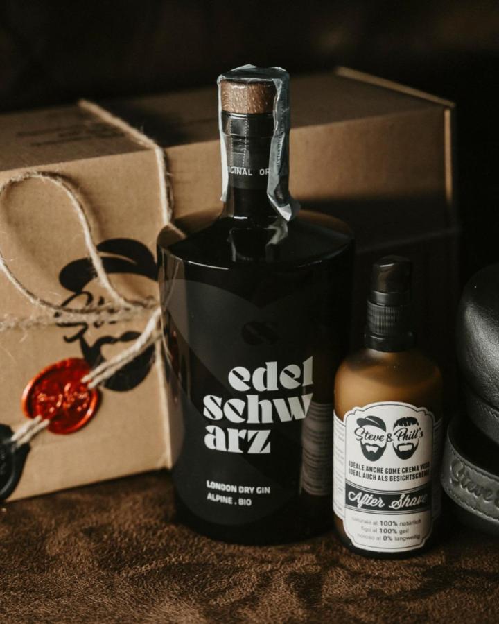 Matte black gin bottle with grooming products from @edelschwarz_. Rustic kraft paper wrapping with twine and wax seals.
