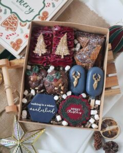 Festive cookie gift box from @the_fat_fairy_ with navy, burgundy, and gold decorated treats.