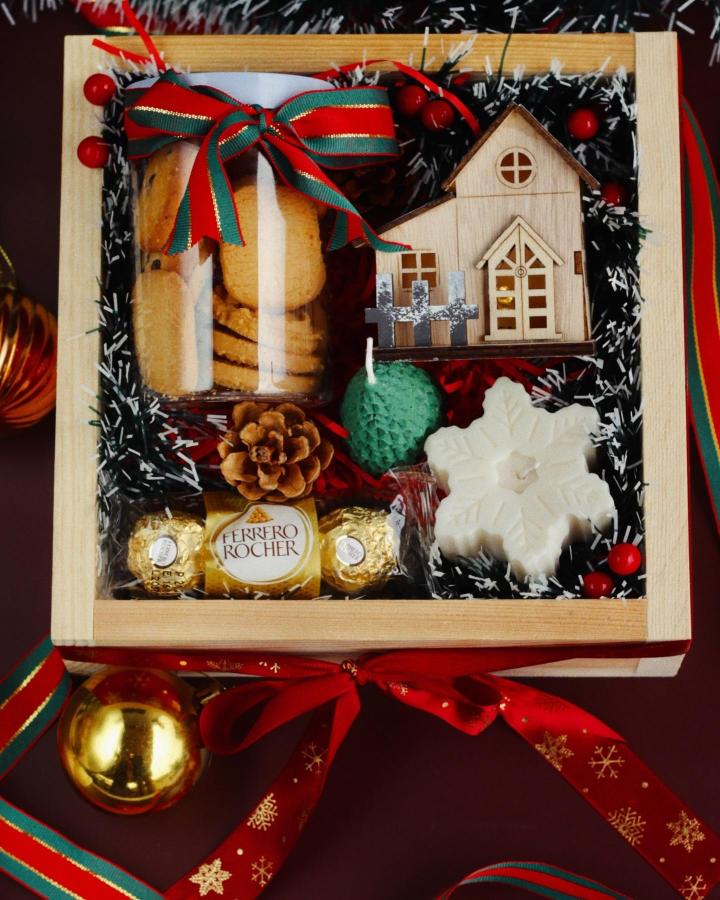 Wooden gift box from @lushbybindi with miniature house, candles, chocolates, and festive ribbon accents.