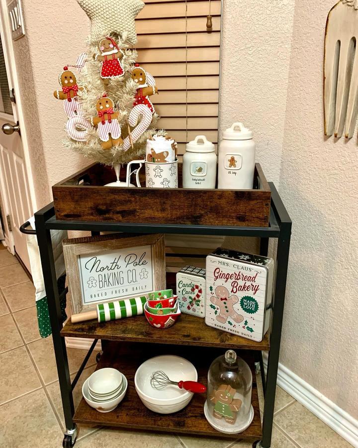 Rustic wood rolling cart from @eulaneutralstyle showcasing christmas hot cocoa bar ideas with gingerbread ornaments and festive signage.