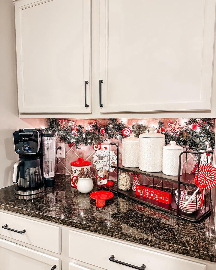 Festive garland and red accents on kitchen counter from @fortheluvofhome with cocoa station setup
