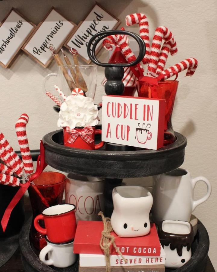 Black tiered tray display from @homebydelaney with red mugs and peppermint decorations for holiday beverage station.