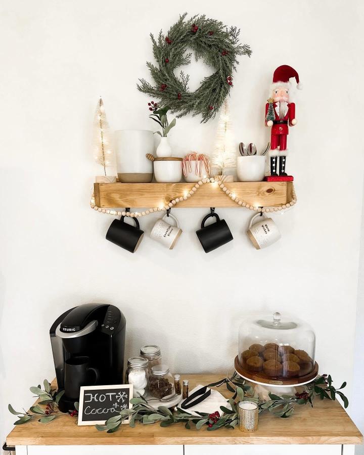 Wooden floating shelf from @cherisekahleblog showcasing christmas hot cocoa bar ideas with festive wreath and nutcracker