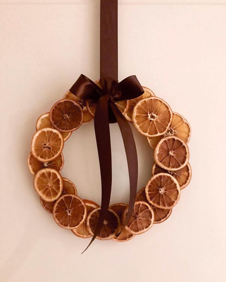 Circular diy dried orange christmas decorations wreath from @flowersandgardenbyanna with brown satin ribbon bow.