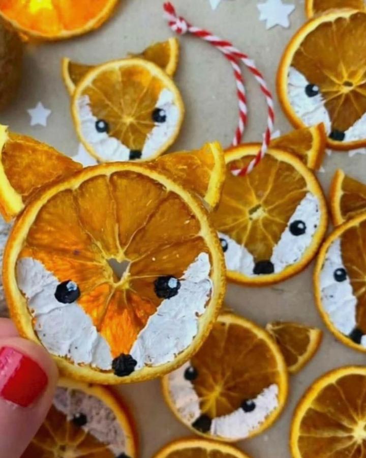 Painted orange slice fox ornaments from @madebyyoustudio with white and black acrylic details and red twine.
