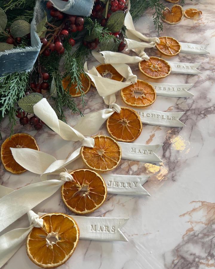 Personalized dried orange place cards with cream ribbon from @nestbyjess featuring handstamped guest names