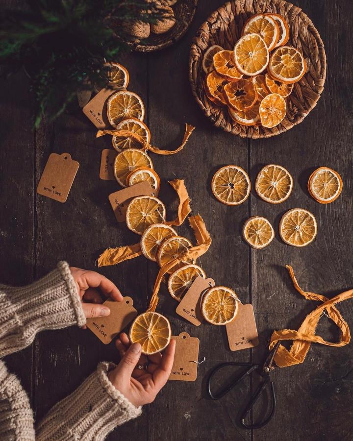 Rustic kraft tags paired with dried citrus slices from @errer.backdrops. Natural gift wrapping elements arranged on dark wood.