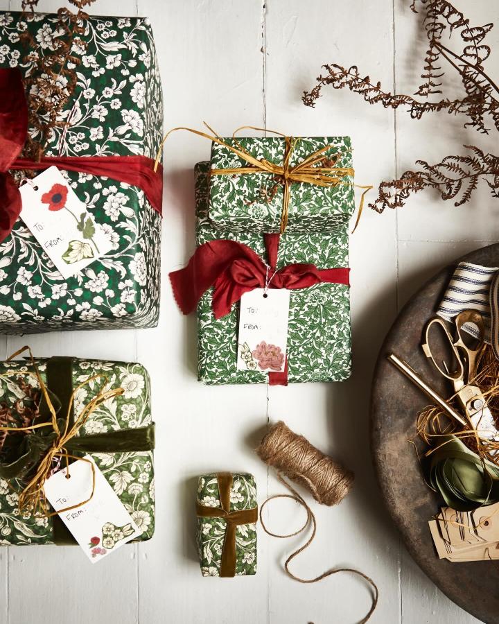 Botanical green floral wrapping paper from @selinalake with velvet ribbon and raffia accents displayed on white wood