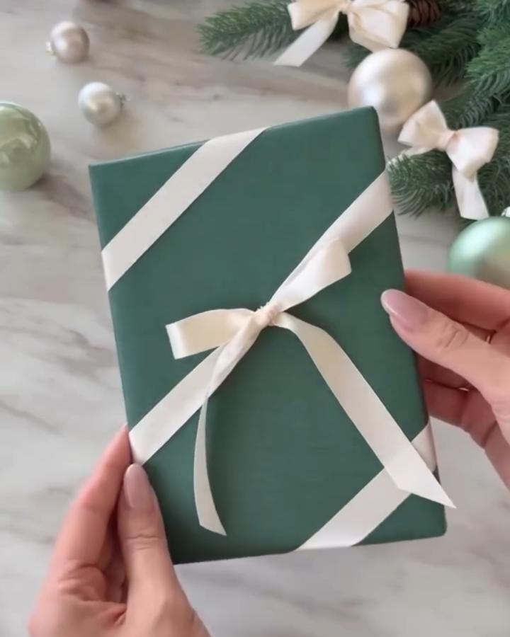 Forest green wrapped gift from @gorgeous_houses_ with diagonal cream ribbon and bow detail.