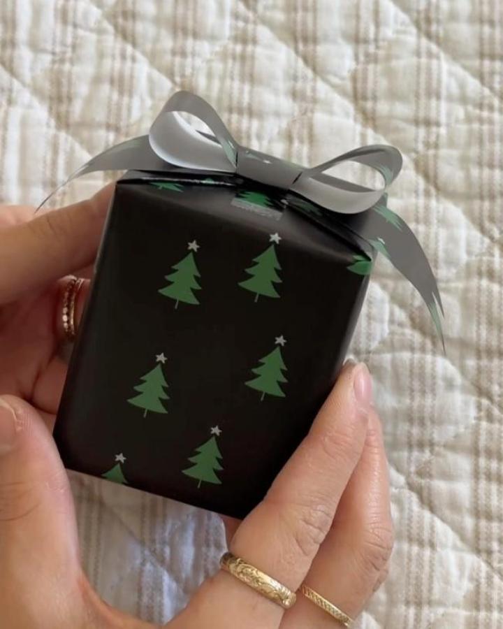 Black paper with green tree pattern gift wrapping from @melanie_locke featuring silver satin ribbon accent.