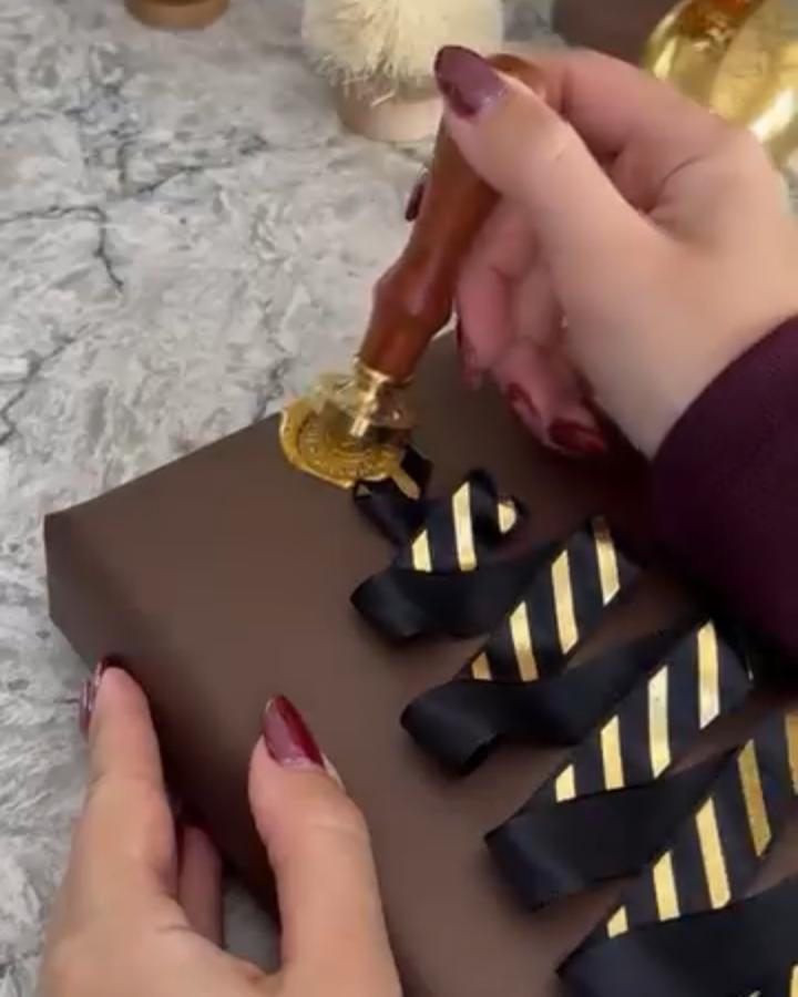 Brown gift box with gold wax seal and striped black ribbon from @elnazhamai showing detailed embellishment technique.
