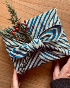 Blue and white striped furoshiki fabric wrap from @nealsyardremedies showing elegant christmas gift wrapping ideas with botanical accents.