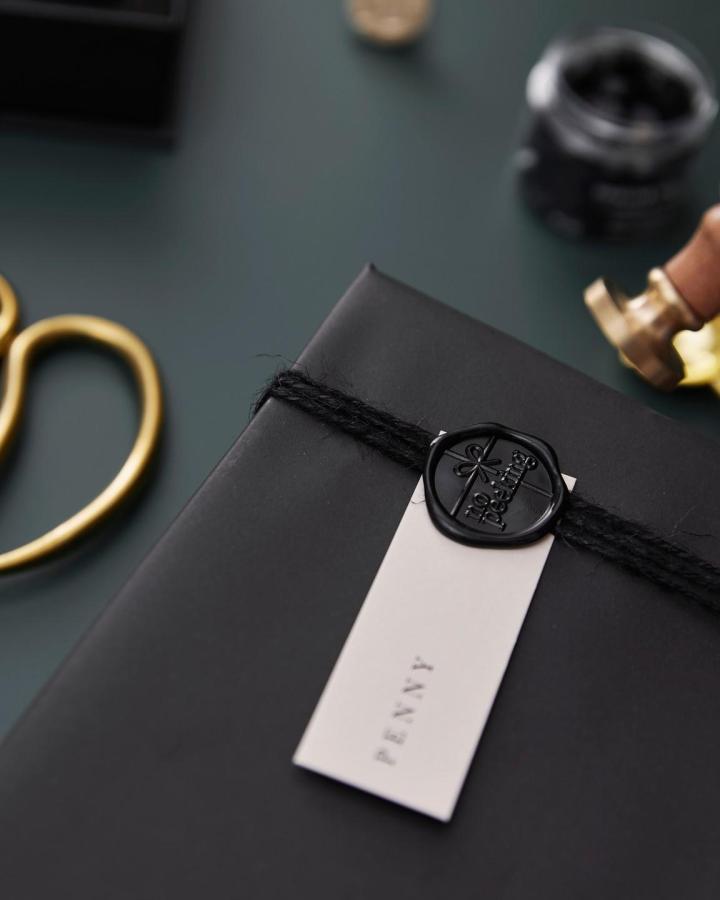 Black wax seal on matte gift wrap from @sea.and.paper with cream tag and twine.