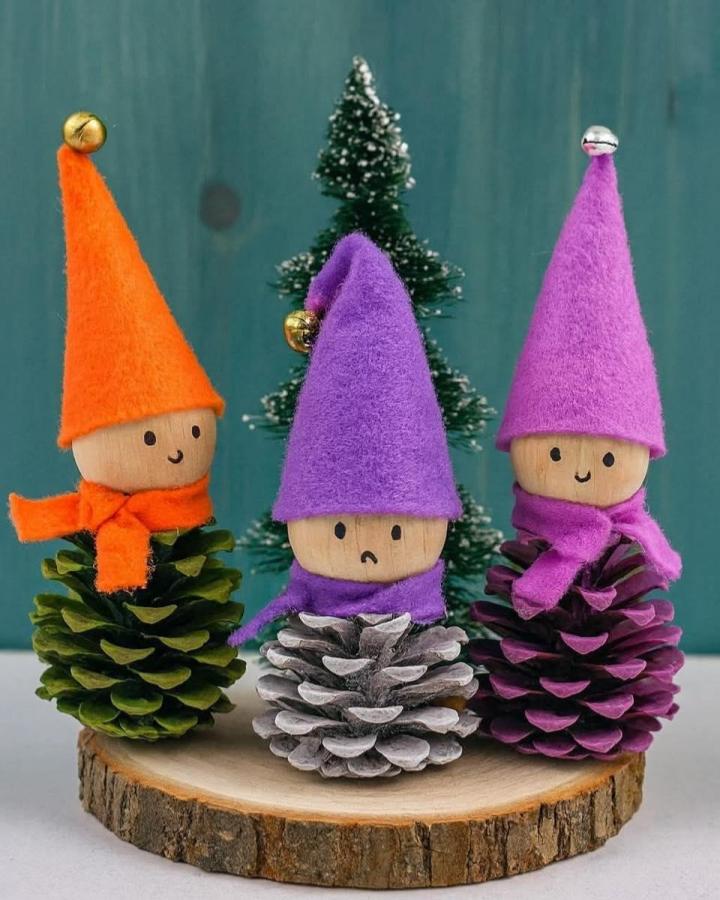 Colorful pinecone gnome ornaments from @juniorsartanddiy with felt hats and scarves on wood slice