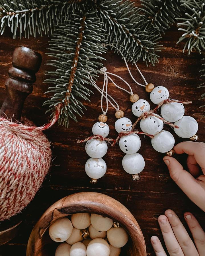 Rustic wooden bead snowman ornaments from @leahdamon perfect for family christmas craft night ideas with painted faces and twine.