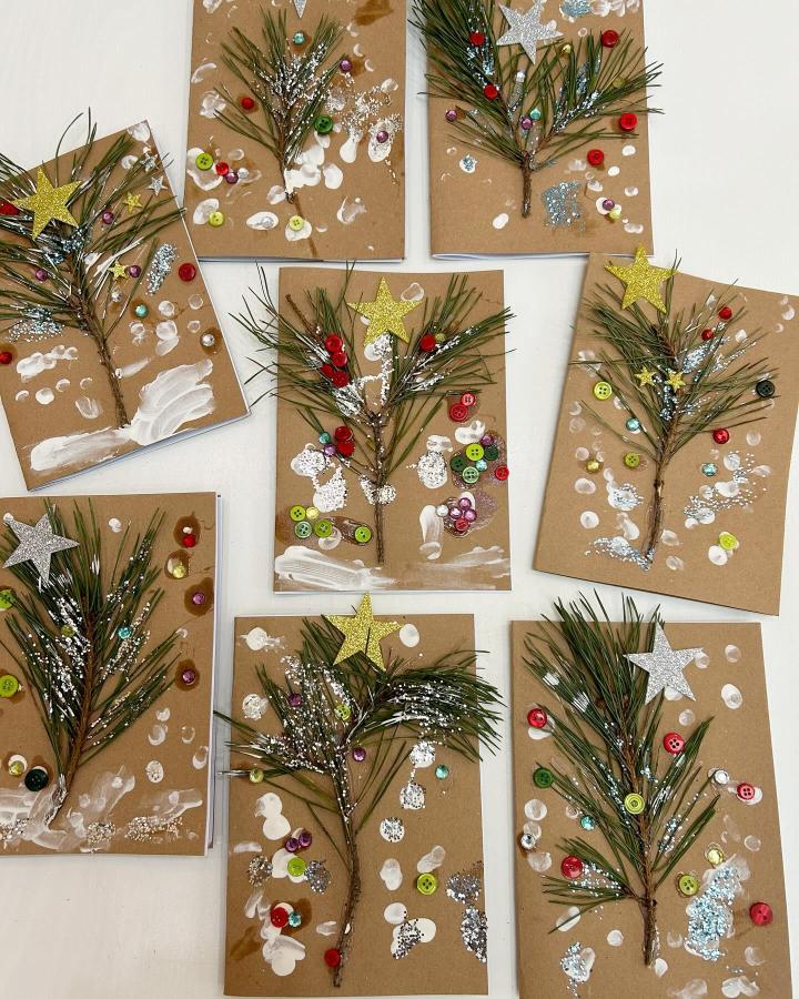 Kraft cardstock Christmas tree cards from @little_house_on_the_green featuring pine branches, buttons, and glitter stars.