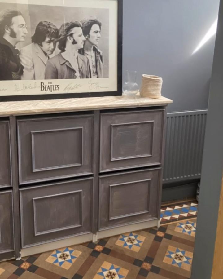 Gray distressed Ikea Bissa cabinet with light wood countertop in a room featuring vintage patterned floor tiles.