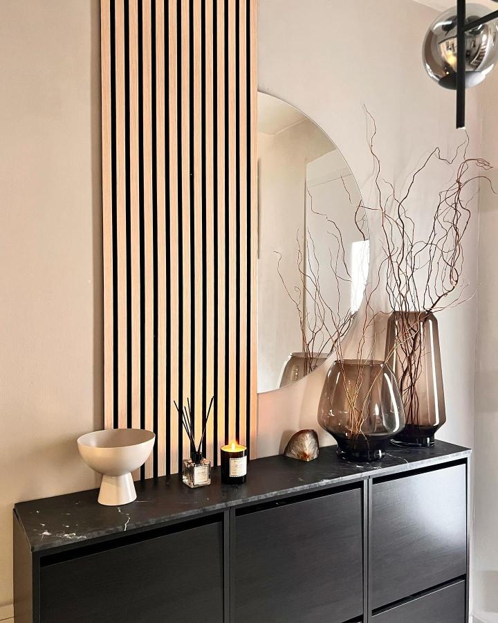 natural wood panel and black Bissa console with glass vases and round mirror from @sesis_home with stylish ikea bissa hacks & ideas