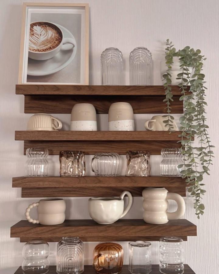 Walnut-stained kitchen shelving from @nita_candles_interior displaying cream ceramics and glassware with trailing eucalyptus.