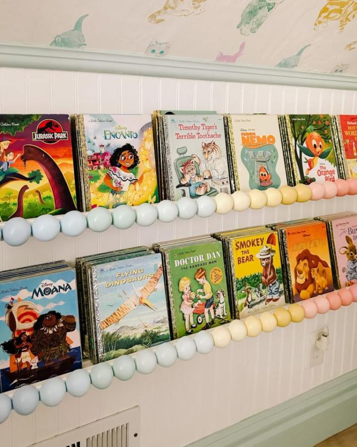 Painted sage green picture ledges from At Home With Ashley. Vintage children's books displayed with ombre bead garland trim.