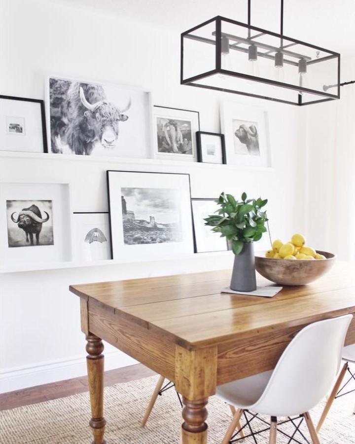 White picture ledges displaying black-framed wildlife prints from @suzisooz. Layered gallery wall styling above wooden table.