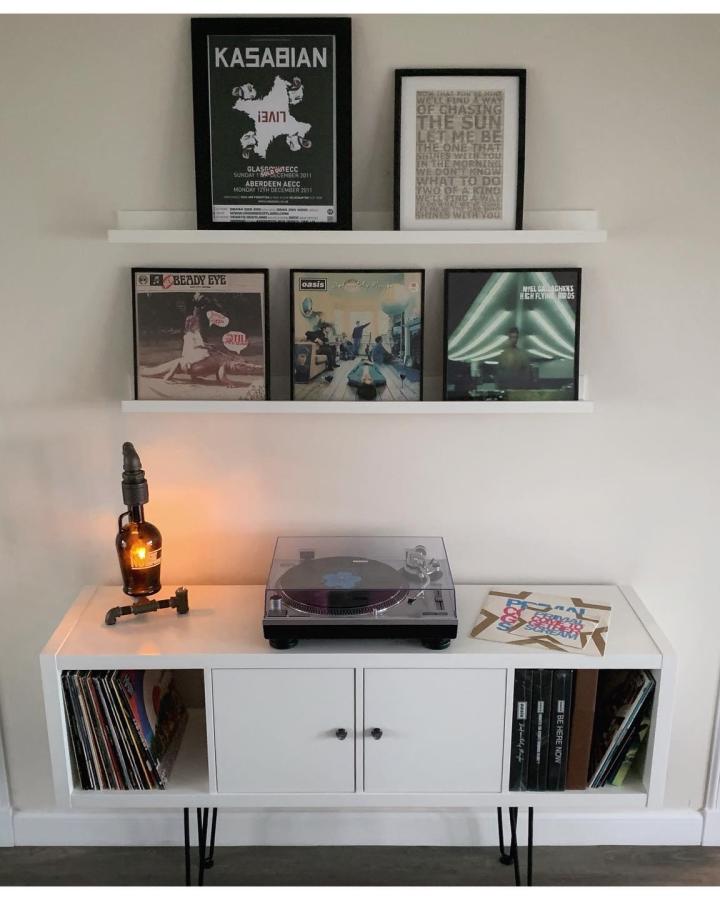 White picture ledges displaying ikea mosslanda hacks & ideas from @carldavey1. Framed vinyl records above turntable station.
