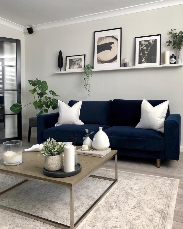 White picture ledges from @homewithgeorgia_ displaying monochrome art above navy sofa in modern living room.