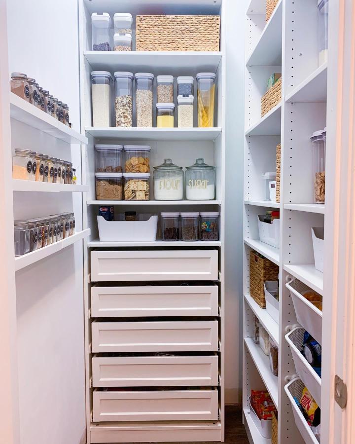 Bright white pantry cabinet from @chatt2chatter. Clear canisters, woven baskets, and deep drawers for tidy storage.