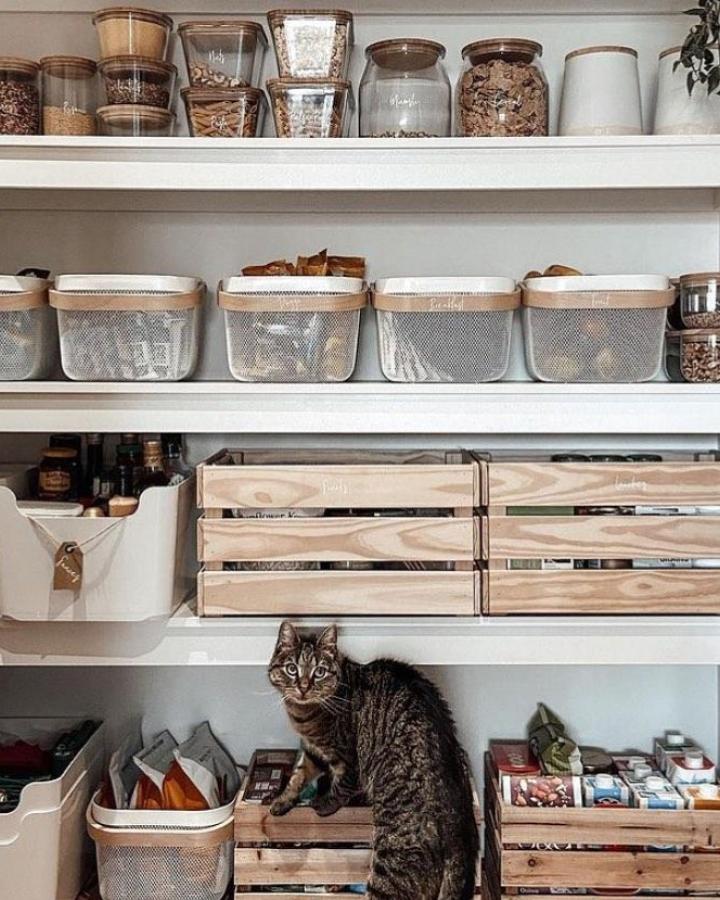 Neutral white and natural wood pantry shelving from @thefeelingsneutral_. Organized bins and crates for ikea pantry ideas.