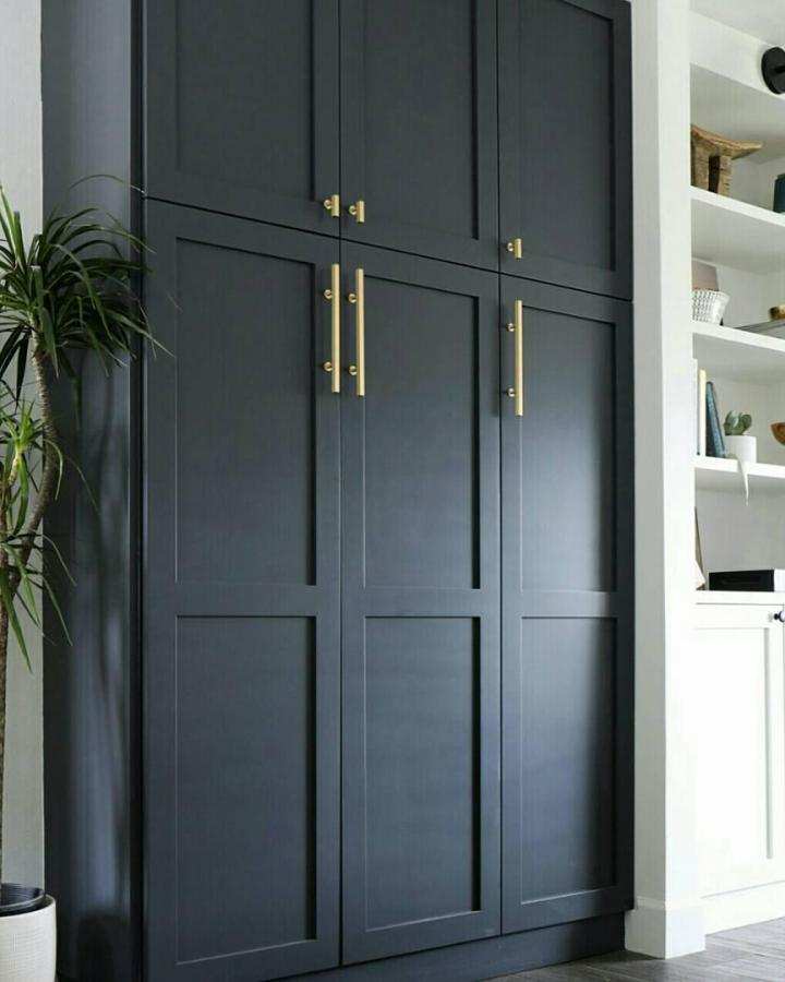 Matte black built-in pantry cabinets from @brittanymakes. Brass pulls and tall doors for a sleek storage wall.
