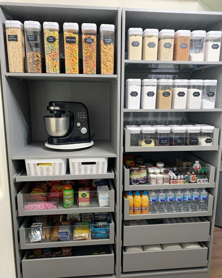 Gray organized pantry cabinet from @confectionsbyj. Clear labeled canisters and pull-out drawers for tidy storage.