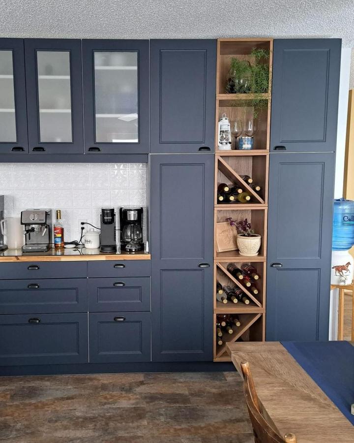 Navy cabinets with warm wood cubby pantry wall from @mkhome_improvements. Open bottle storage tower and coffee station.