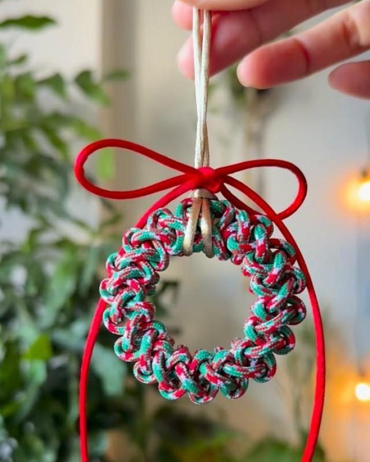 Multicolored twisted wreath macrame christmas ornament ideas from @macramewithaya featuring red teal and cream cords with ribbon accent