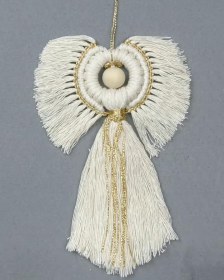 White and gold angel ornament from @share.the.knot featuring layered wings and flowing fringe details.