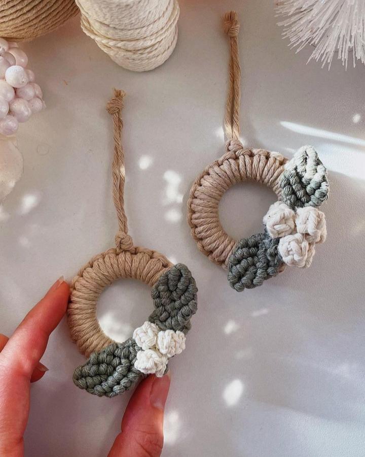 Beige and gray-green wrapped ring ornaments from @macrame_decor_by_katerina. Knotted flowers accent minimalist wreath design.