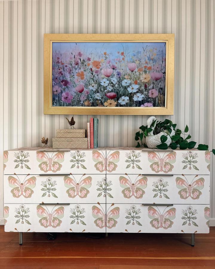 Soft pastel butterfly pattern on dresser from @ponderosa_and_plaid brightens room with peel & stick wallpaper ideas and floral artwork.
