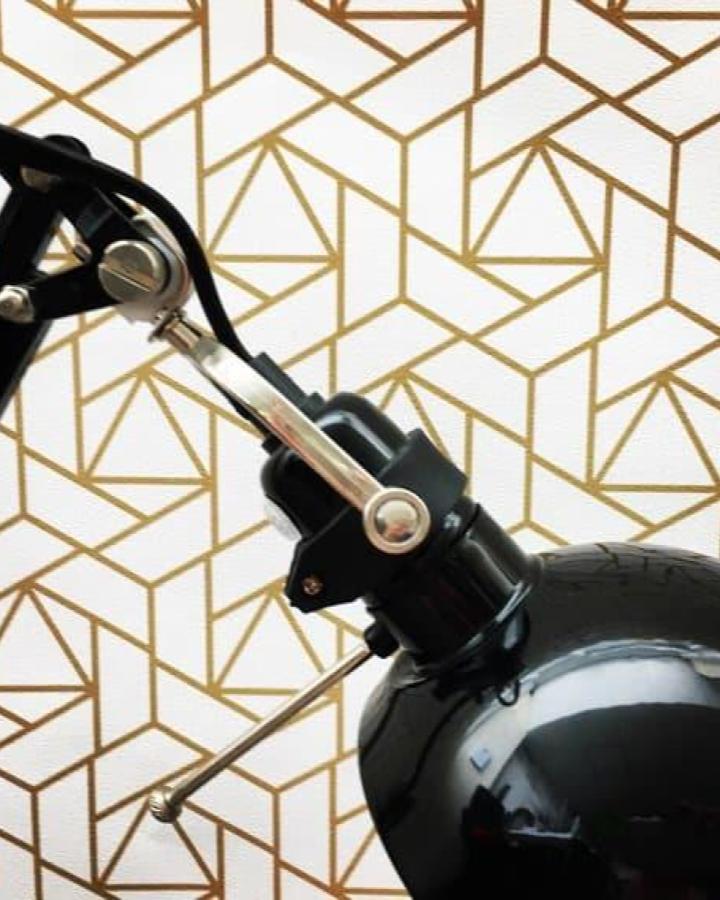 Gold geometric peel & stick wallpaper ideas from BonnieBoldWallpaper on Etsy with modern lines and white background behind a black desk lamp.