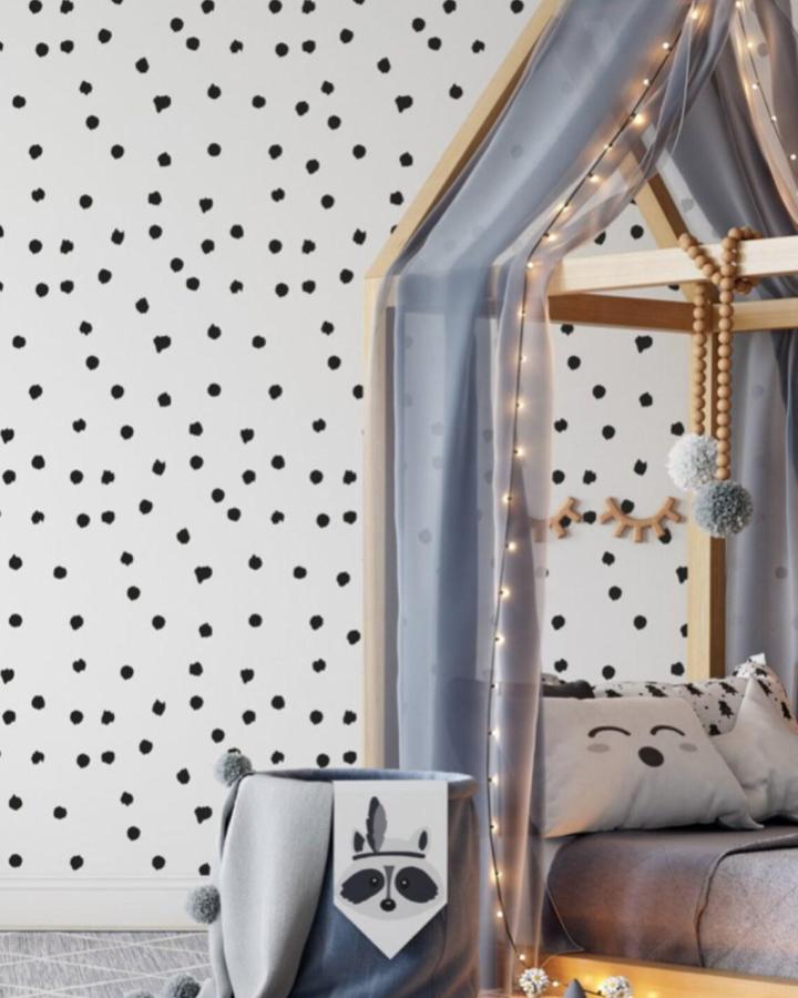 Black and white spotted peel & stick wallpaper ideas in a child's bedroom with soft curtains and playful decor.