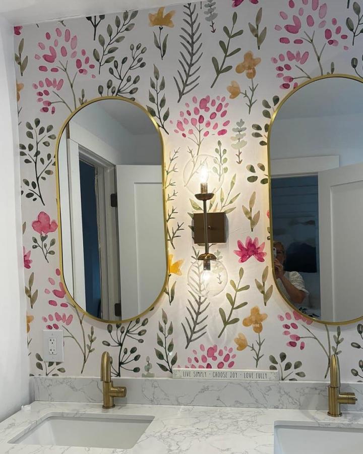 Floral watercolor peel & stick wallpaper in a stylish bathroom with brass accents and marble countertop.