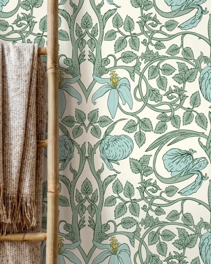 Leafy green and blue floral wallpaper on cream background with bamboo ladder and woven throw showcasing peel & stick wallpaper ideas.