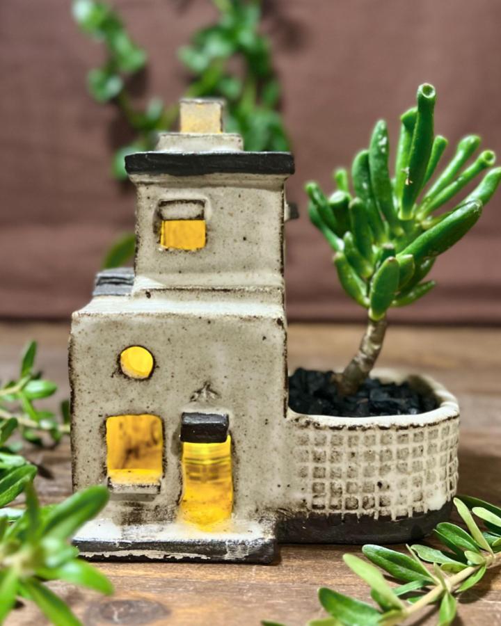 Beige ceramic miniature house planter from @littletree.studio with succulent planter ideas and glowing windows.