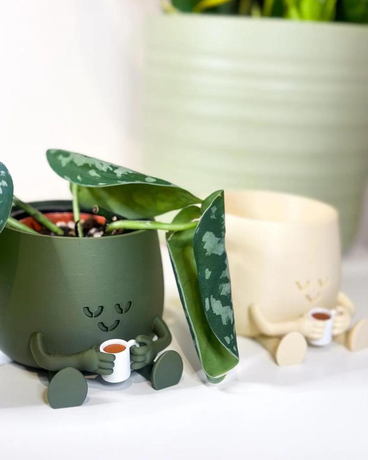 Whimsical green and cream ceramic planters from LeafyLayersStudios holding small plants with tiny arms and cups.