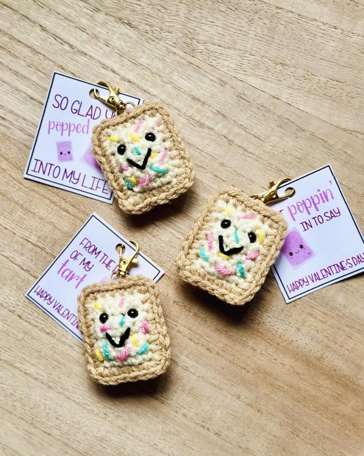 Beige crochet toast keychains with colorful sprinkles and smiling faces from @dayscrochetnc. Cute crochet valentines ideas for small gifts.