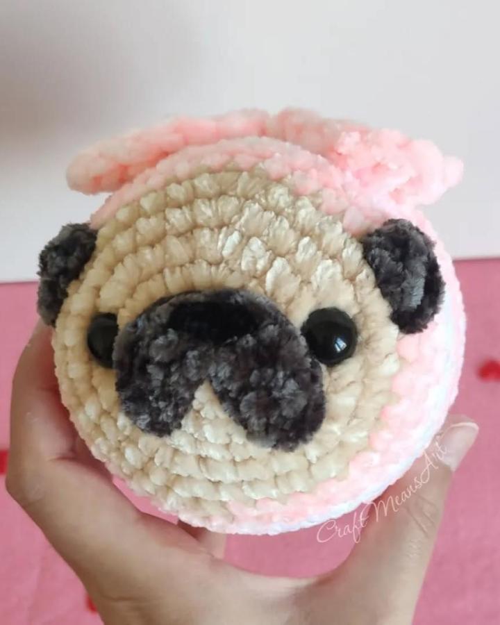 plush beige and black crochet pug on pink background from @craftmeansart soft textured crochet valentines ideas toy