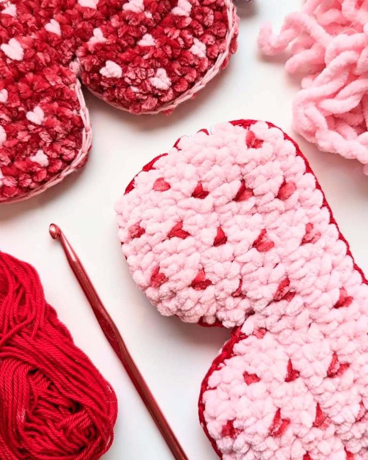 plush pink and red chunky yarn crochet hearts with small heart details from @yarnyogicrochet cozy crochet valentines ideas craft