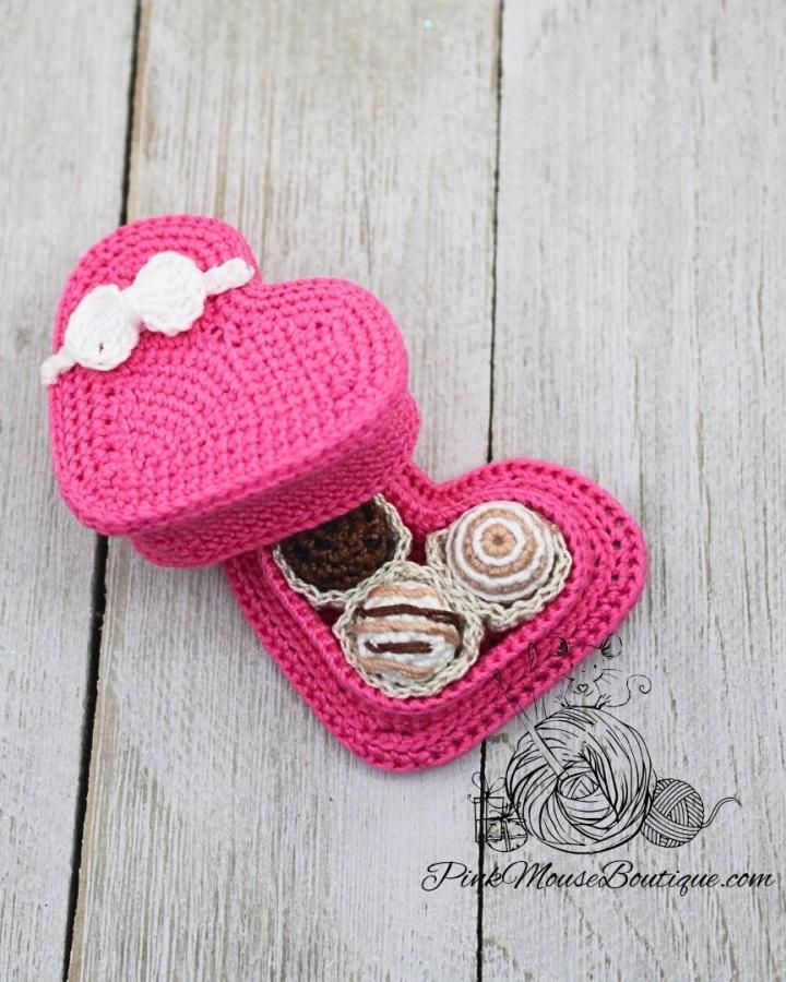 Bright pink crocheted heart box with small cream and brown yarn chocolates inside from @pinkmouseboutique perfect crochet valentines ideas gift box