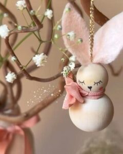 Soft pink and natural wood bunny ornament with delicate painted features from @vanessa.sews.magic hanging on branch easter bunny crafts for adults