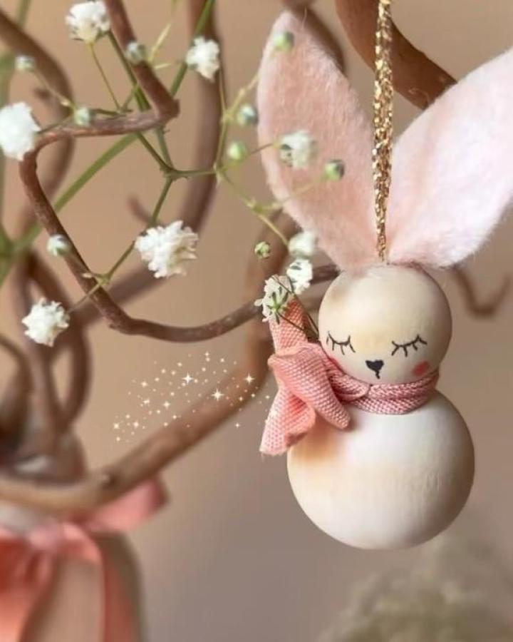 Soft pink and natural wood bunny ornament with delicate painted features from @vanessa.sews.magic hanging on branch easter bunny crafts for adults