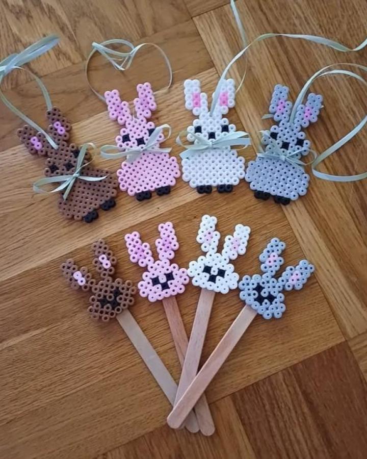 Pastel perler bead Easter bunny crafts for adults with ribbons and wooden sticks on wooden floor from @beadsbyhama.