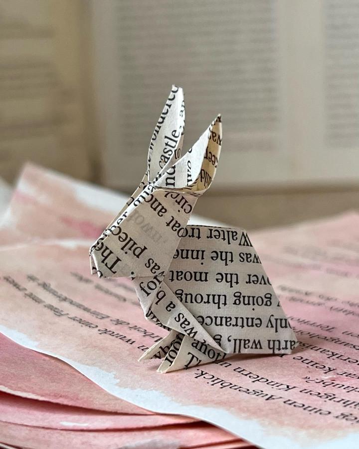 Vintage book page origami bunny sitting on layered pink paper for easter paper crafts for adults from @heinzundbrummel.